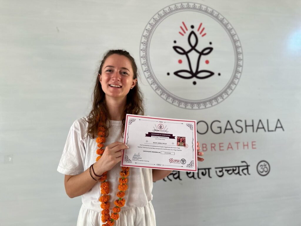 Eine junge Frau hält eine Bescheinigung in die Höhe.