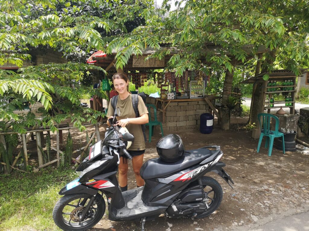 Eine junge Frau steht hinter einem Moped.