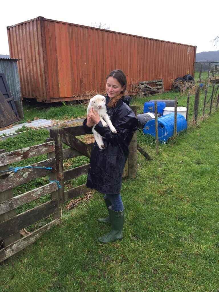 Eine junge Frau trägt ein Lamm.