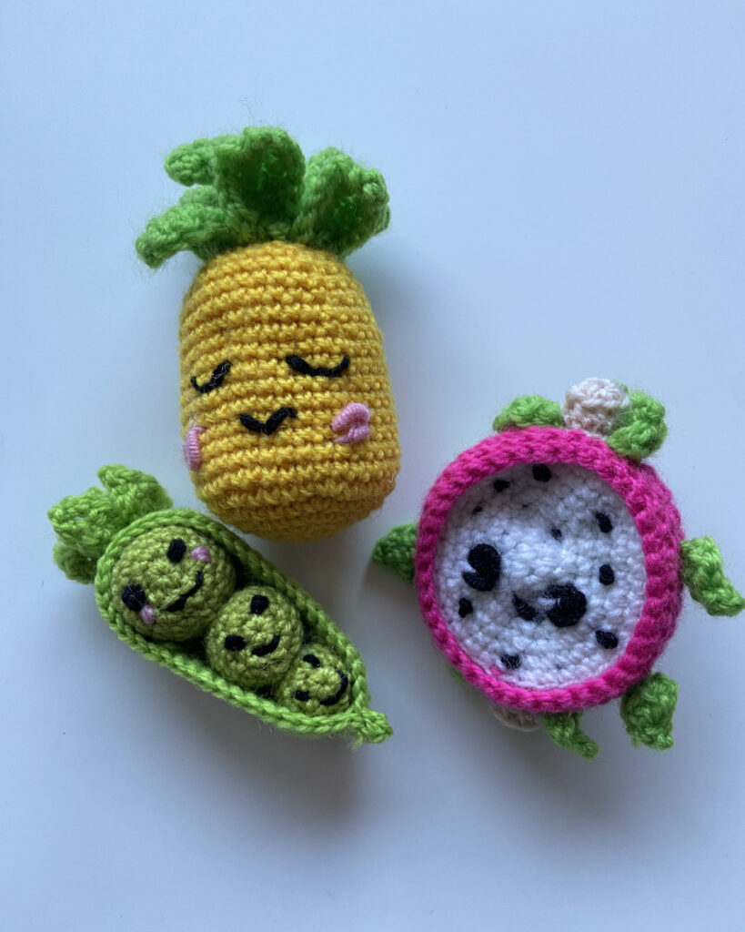 Eine Ananas, eine Drachenfrucht und drei Erbsen in einer Schale mit Gesichtern (Amigurumis)