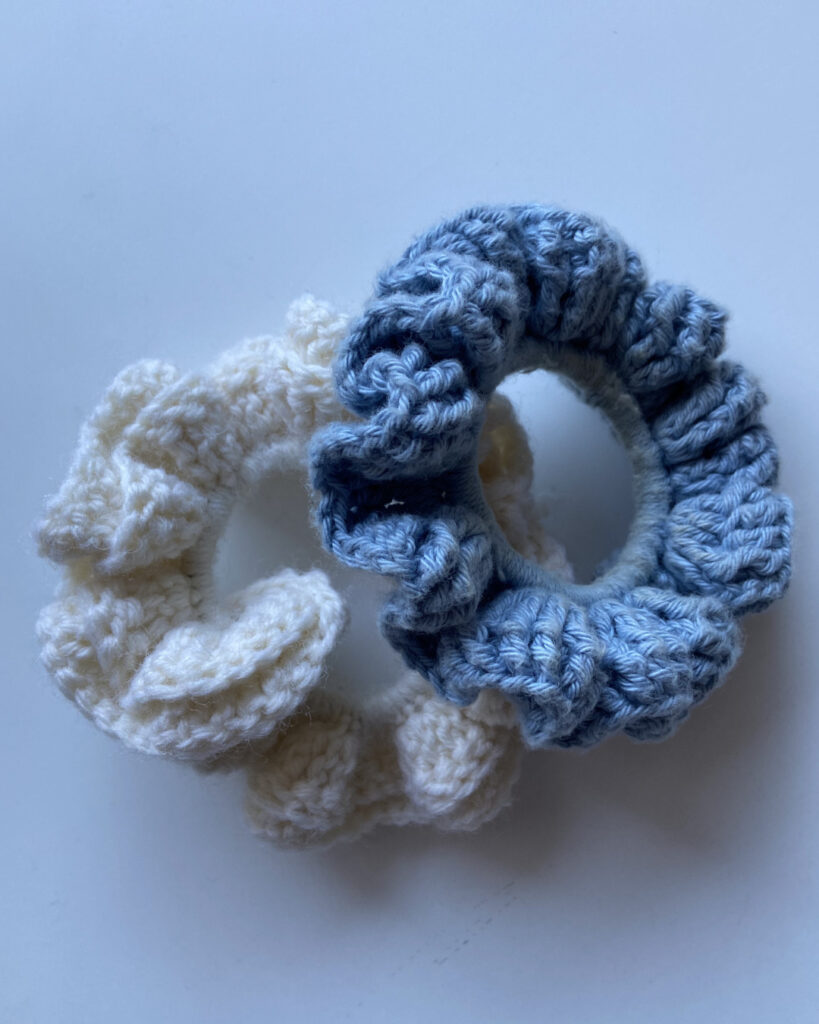 Ein weißes und ein blaues Haargummi (gehäkelt).