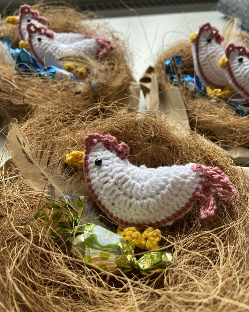 Im Vordergrund ist ein Nest mit einem gehäkelten weißen Huhn.