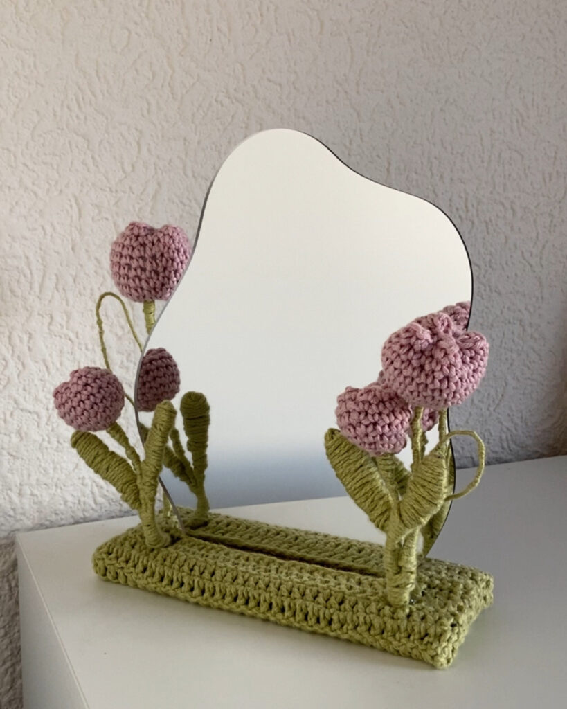 Ein Spiegel mit gehäkelten rosa Tulpen am Rand.