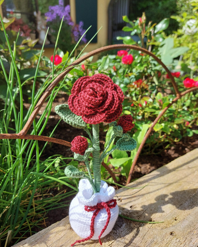 gehäkelte Rose in einem weißen Säckchen.